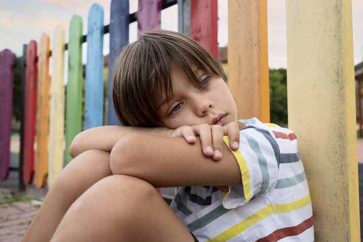 Niño triste víctima de bullying en Bilbao sentado solo en el colegio.