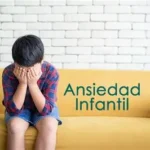 Niño sentado en un sofá con la cabeza entre las manos, mostrando signos de ansiedad infantil.
