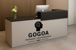 Recepción moderna del centro de psicología GOGOA con un mostrador beige y el logotipo del centro en la parte frontal.