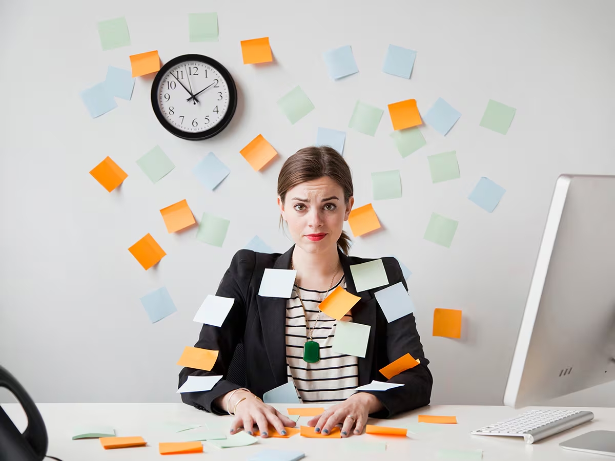 Mujer sentada en el suelo rodeada de post-its con tareas pendientes sosteniendo una taza de té
