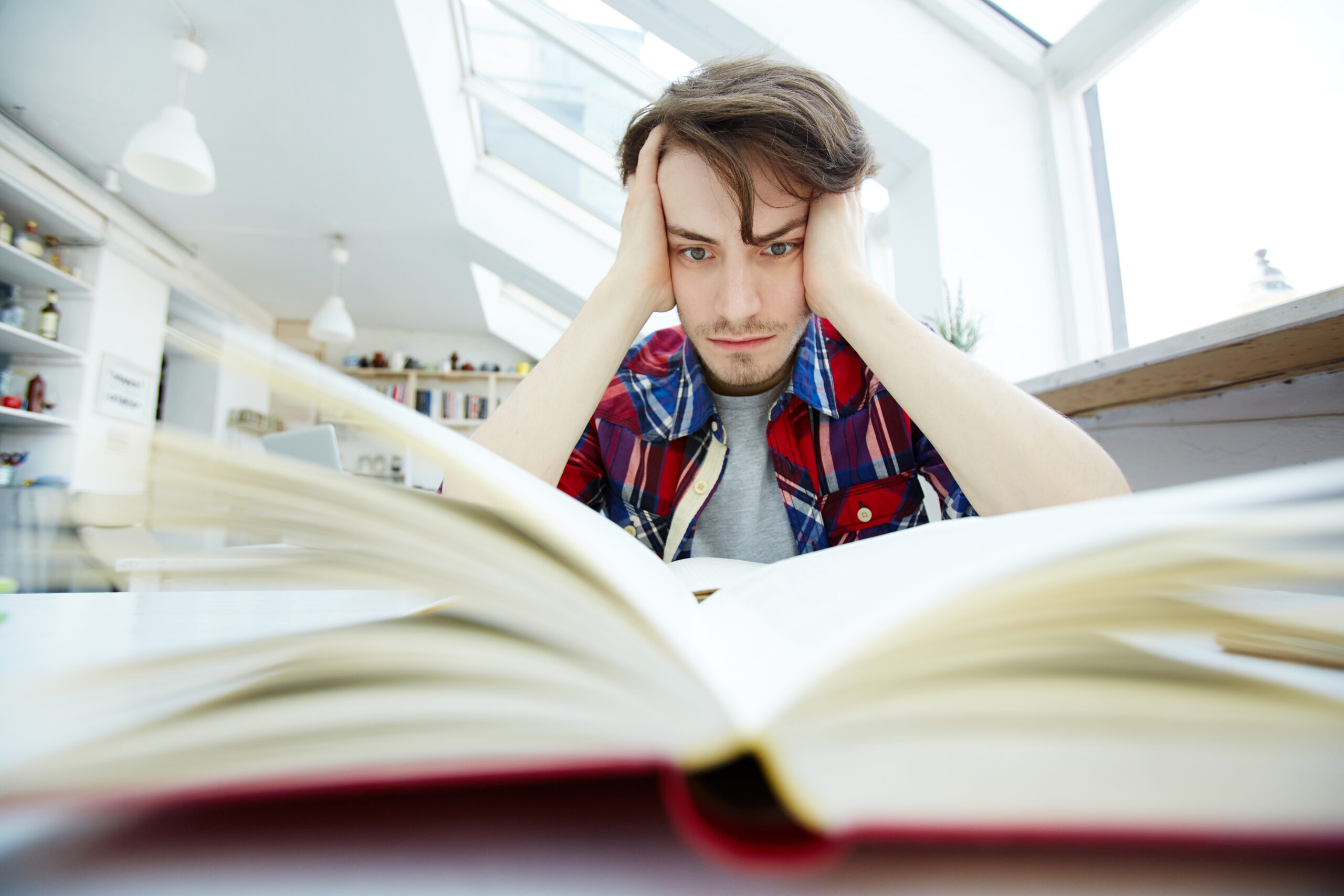 Adolescente en habitación con mirada perdida, rodeado de libros y apuntes, reflejando presión interna