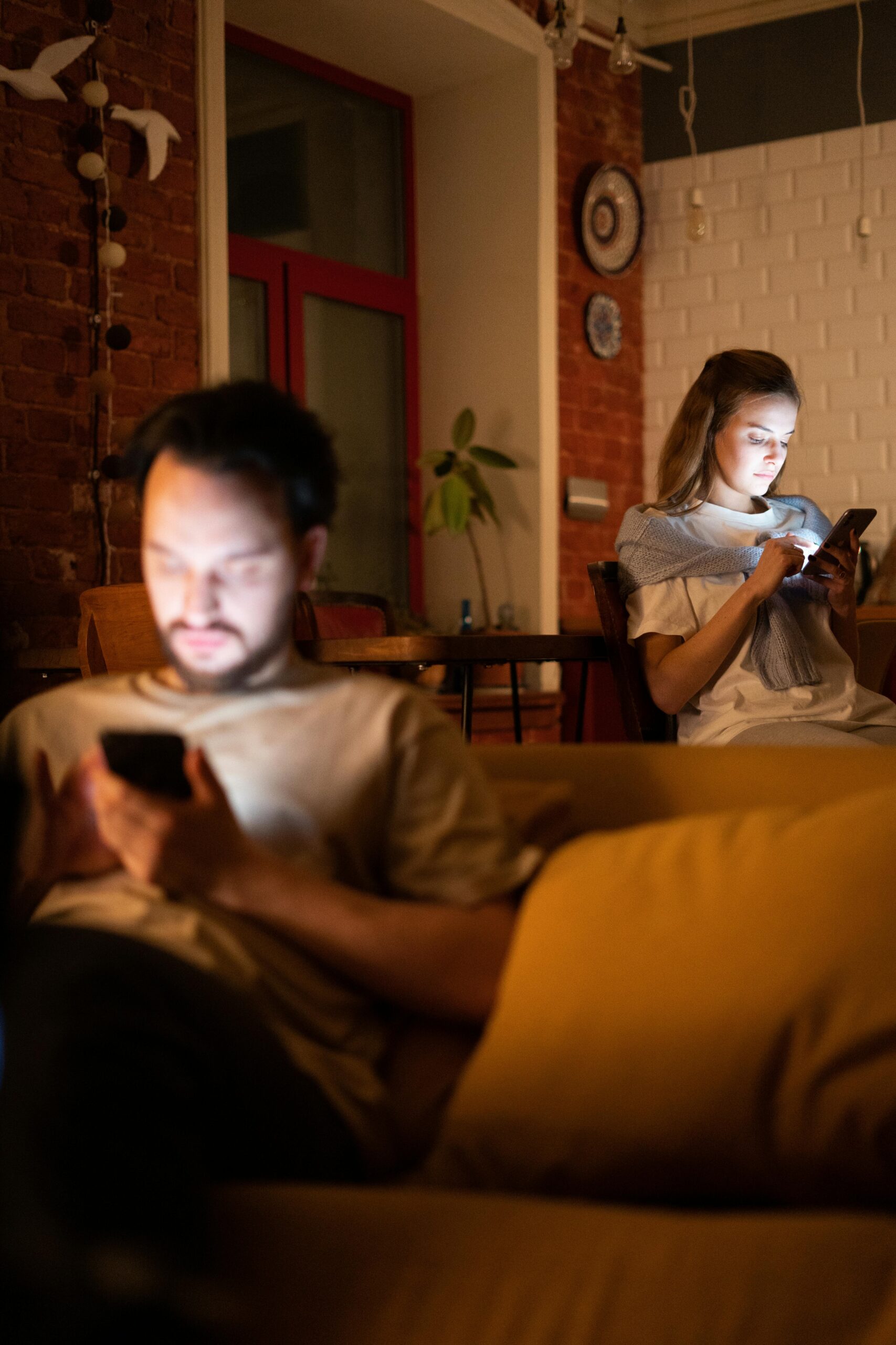 Pareja en el sofá con distancia física mirando cada uno su móvil